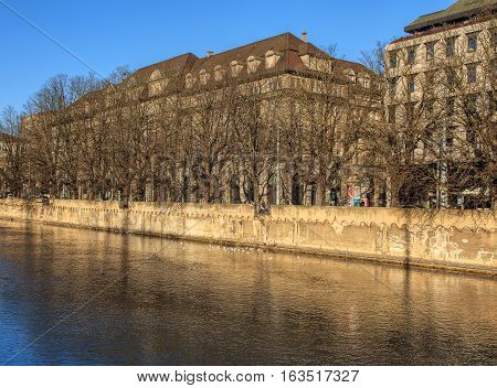 Zurich, Switzerland - 27 December, 2016: the Limmat river, trees and buildings along it in wintertime. The Limmat is a river that commences at the outfall of Lake Zurich in the southern part of the city of Zurich and flows in northwesterly direction.