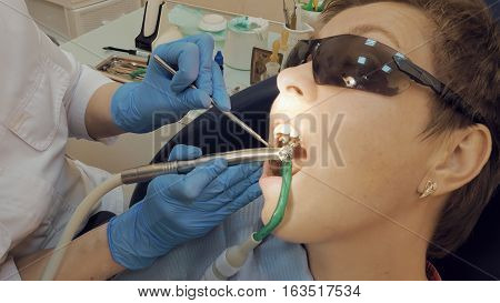 Woman at the dentist clinic office gets dental medical examination and treatment. Close up shot. Odontic and mouth health is important part of modern human life that dentistry help with.