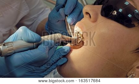 Woman at the dentist clinic office gets dental medical examination and treatment. Close up shot. Odontic and mouth health is important part of modern human life that dentistry help with.
