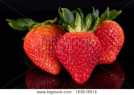 Three strawberries isolated on a black background