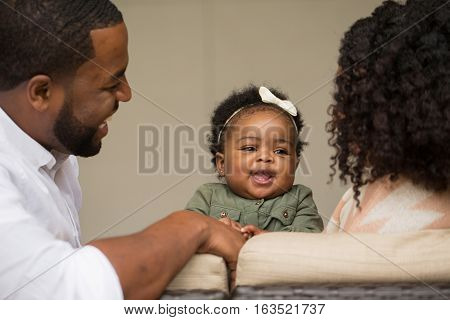 African American Family playing and laughing with their daughter.