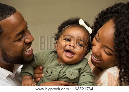 African American Family playing and laughing with their daughter.