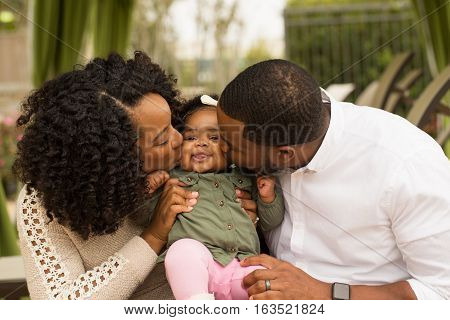 African American Family playing and laughing with their daughter.