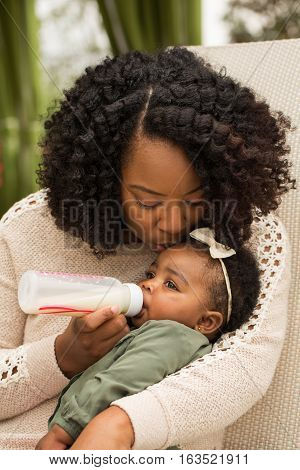 African American woman feeding her daughter with a bottle.