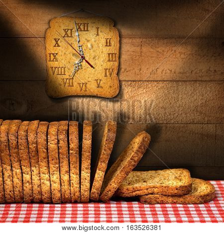 Rusks of wholemeal flour on a table with red and white checkered tablecloth with a clock made with a rusk. Concept of time for a healthy breakfast
