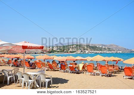 KALYVES, CRETE - SEPTEMBER 16, 2016 - Tourists relaxing on the beach with views towards the mountains Kalyves Crete Greece Europe, September 16, 2016.