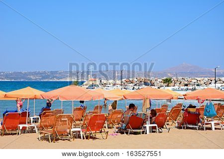 KALYVES, CRETE - SEPTEMBER 16, 2016 - Tourists relaxing on the beach with views towards the mountains Kalyves Crete Greece Europe, September 16, 2016.