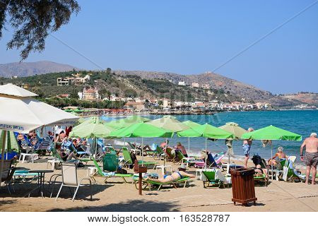 KALYVES, CRETE - SEPTEMBER 16, 2016 - Tourists relaxing on the beach with views towards the mountains Kalyves Crete Greece Europe, September 16, 2016.