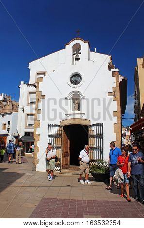 TOSSA DE MAR, SPAIN - OCTOBER 06, 2013: People are walking on street near Chapel of Mare de Deu del Socors in Tossa de Mar, Spain