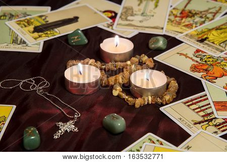 Moscow, Russia - December 4, 2016: Rider-Waite tarot cards with runes and burning candle. Esoteric background.