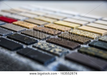 Center focus on different colored kitchen and bath stone counter top samples, with front and back of image blurred so focus is in the middle.