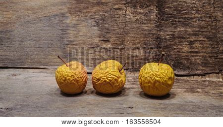 Three shriveled  old yellow apples. Wooden background