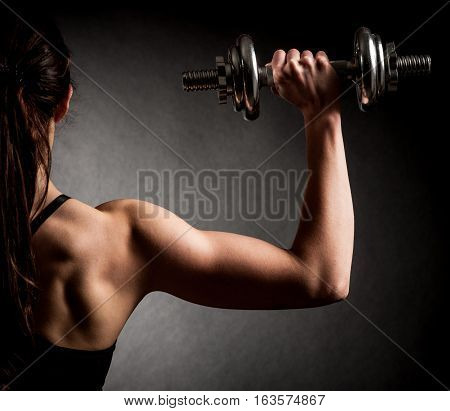 Atractive Fit Woman Works Out With Dumbbells As A Fitness Conceptual Over Dark Background