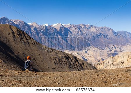girl with a backpack sitting and looking at the mountains, pass Gyu La, Nepal