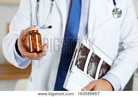 Male Medicine Doctor Hand Holding And Offering To Patient Jar Of Pills