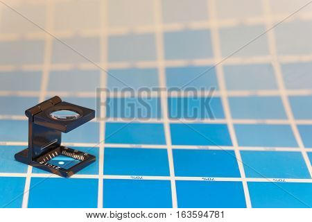 Magnifier or printer's loupe sits on a cyan test sheet in a pre-press workshop when proofing