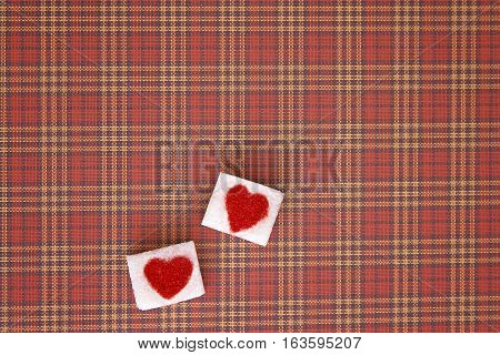 Sugar cubes with a red heart on one of them as background. Top view. Diet unhealty sweet addiction concept
