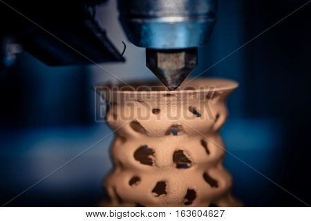 3D printer prints from the plastic figure closeup. 3D printer makes yellow model close-up on gray flat surface
