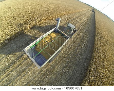 Aerial sot of a JD tractor and JD track driven grain cart hauling corn.