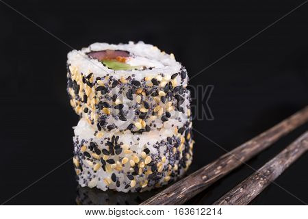 Two rollas sesame and salmon on a black background