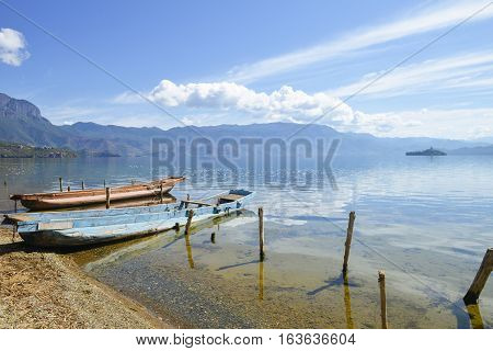 Two abandoned wooden boats sitting on bank of Lugu Lake, in Lijiang, Yunnan, China