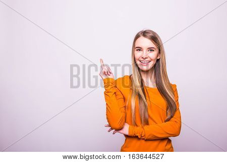 Happy Blonde Girl In Orange T-shirt Pointed With Finger Up On White
