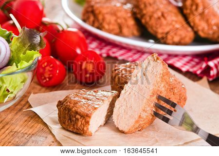 Meatballs with salad and cherry tomatoes on baking paper.