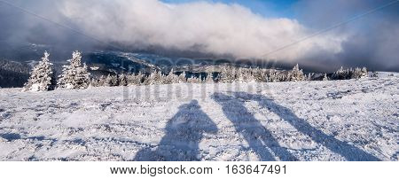 winter mountain meadow with small shrubs, hills on the background, shadows and blue sky with clouds bellow Stuhleck hill in Fischbacher Alpen mountains in Styria
