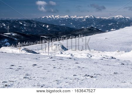 winter austrian Alps panorama with snow, mountain peaks and blue sky with clouds from Pretulalpe hill in Stuheck mountain ridge in Fischbacher Alpen mountain range in Styria
