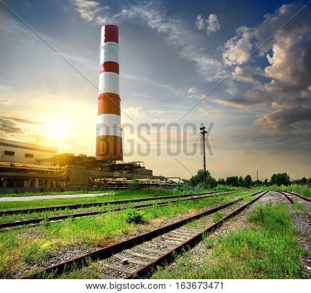 Railroad and industrial tube under cloudy sky