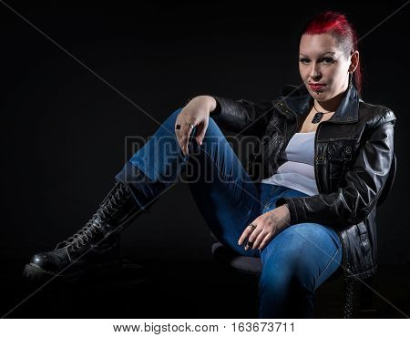 Sitting frick woman with shaved head on black background