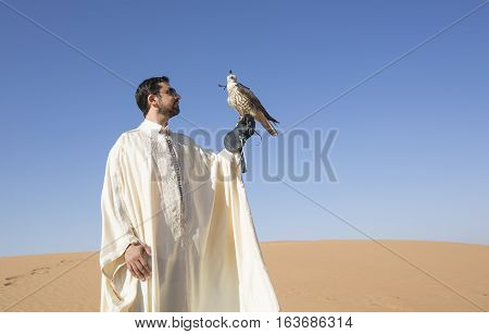 Dubai, UAE, December 3rd, 2016: Tunisian man with a seaker falcon in a desert at sunrise