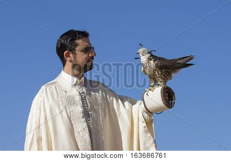 Dubai, UAE, December 3rd, 2016: Tunisian man with a seaker falcon in a desert at sunrise
