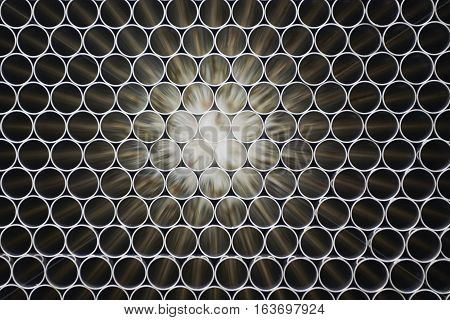Industrial background. Close up of internal metal pipes in a warehouse. Stack of new and shiny steel pipe in factory.
