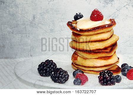 Pancakes with berries on white plate. Tined textured retro style image