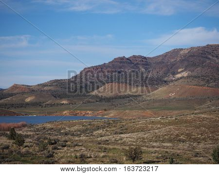 A pond with rugged hills in the background at the Painted Hills Unit of the John Day Fossil Beds in Eastern Oregon on a sunny spring day.