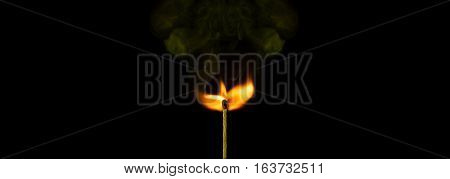 Macro of a burning matchstick flame in the dark.