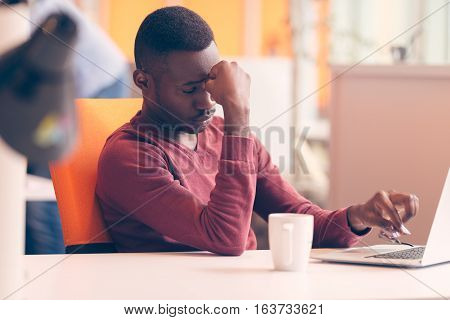 Handsome successful African American looking at the screen with serious face expression at modern startup office.