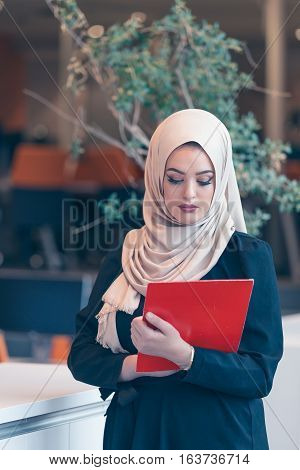 Arabian business woman holding a folder and talking on the phone isolated on white