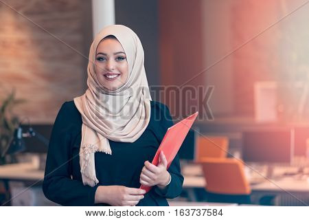 Arabian business woman holding a folder and talking on the phone isolated on white
