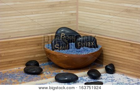 black lava stones massage and a wooden bowl with lavender salt