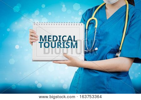 Doctor Shows Medical Tourism Text On White Line Paper Book.