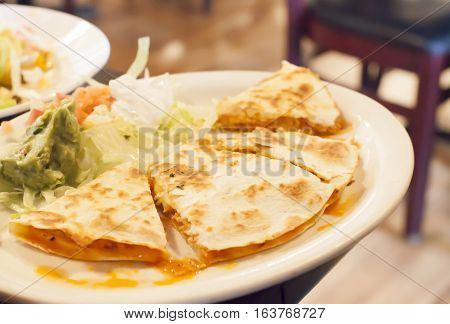 Chicken quesadilla lettuce tomato and guacamole on a plate