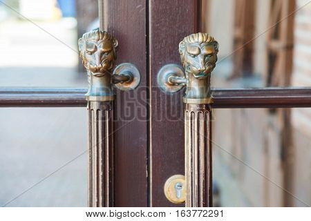 old style wooden door with handles in the form of lion's head.