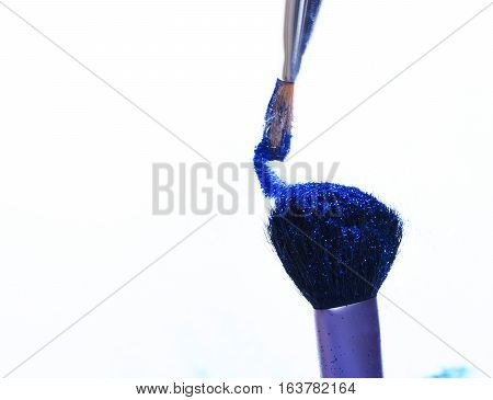 soft cosmetics brushes with blue sparkle glister isolated on white copy space