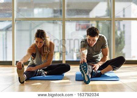 Two People Streching Their Legs In Gym.