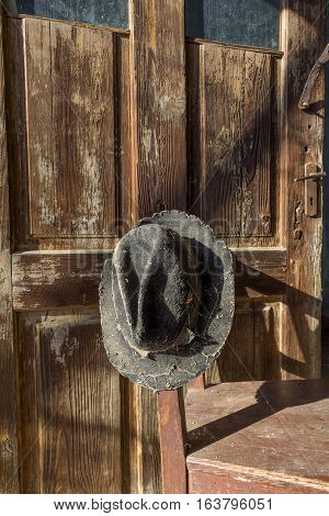 Battered old hat damaged by clothes moth on vintage background. A forgotten hat covered with spider web among the ruins of a house. Imagine the owner of this hat and tell their story.