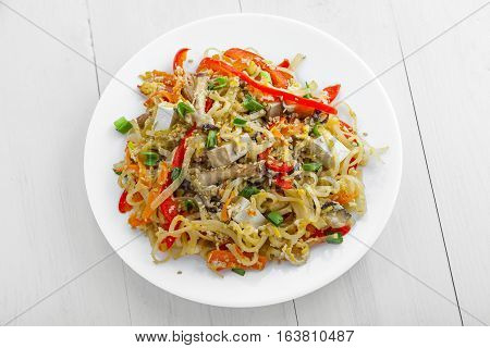 Plate of stirred rice noodles with tofu vegetables and shiitake on a table. Traditional Asian cuisine meal. Top view.