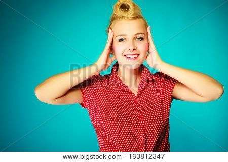 Shocking amazed astonished gestures concept. Shocked lovely pin up young girl holding head with hands. Studio shot on blue background