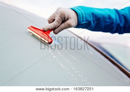 Woman Deicing Front Car Windshield With Scraper